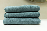 Stack of three blue towels on a white surface with a neutral background