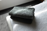 Folded dark gray towel on a textured white surface