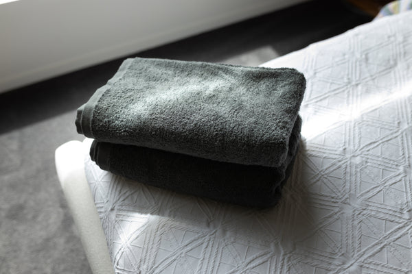 Folded dark gray towel on a textured white surface