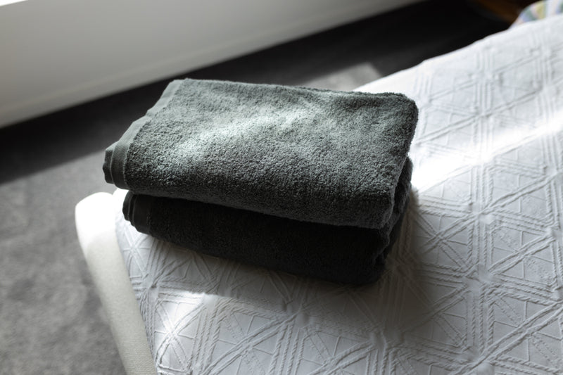 Folded dark gray towel on a textured white surface
