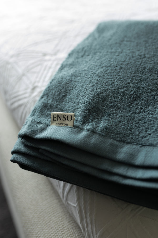 Teal towel with 'ENSO' label on a textured surface