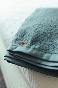 Teal towel with 'ENSO' label on a white surface