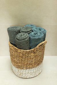 Wicker basket with rolled-up towels on a light background