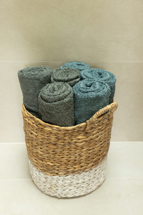 Wicker basket with rolled-up towels on a light background