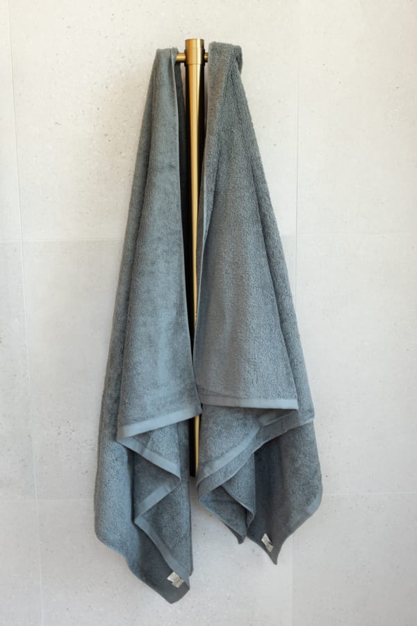 Gray towel draped over a gold towel rack on a white wall