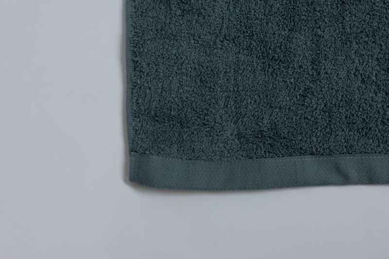 Dark green towel corner on a light gray background