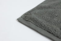 Close-up of a gray textured rug corner on a light gray background